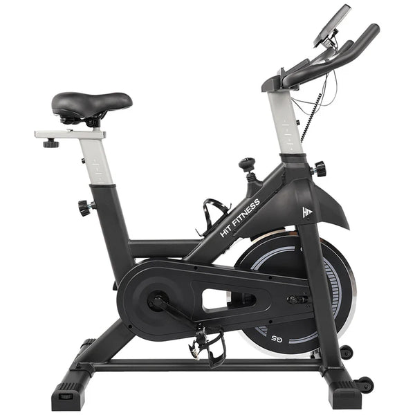 The image shows a HIT Fitness spin bike with a black and silver frame. It features adjustable handlebars and seat, a large flywheel, and foot straps on the pedals for a secure cycling experience.