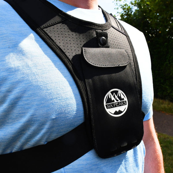 Close-up of the Six Peaks Running Vest with Phone Holder, showing the front pouch and logo while being worn by a person.