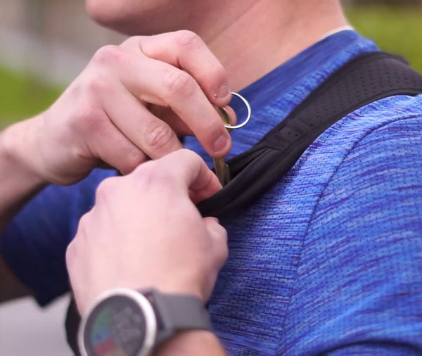 Person attaching keys to the shoulder pocket of the Six Peaks Running Vest with Phone Holder.