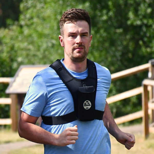 Person running outdoors wearing the Six Peaks Running Vest with Phone Holder, featuring a front phone pouch and adjustable straps.