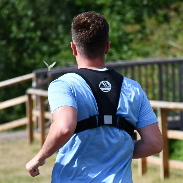 Person running outdoors wearing the Six Peaks Running Vest with Phone Holder, showing the back view with adjustable straps.