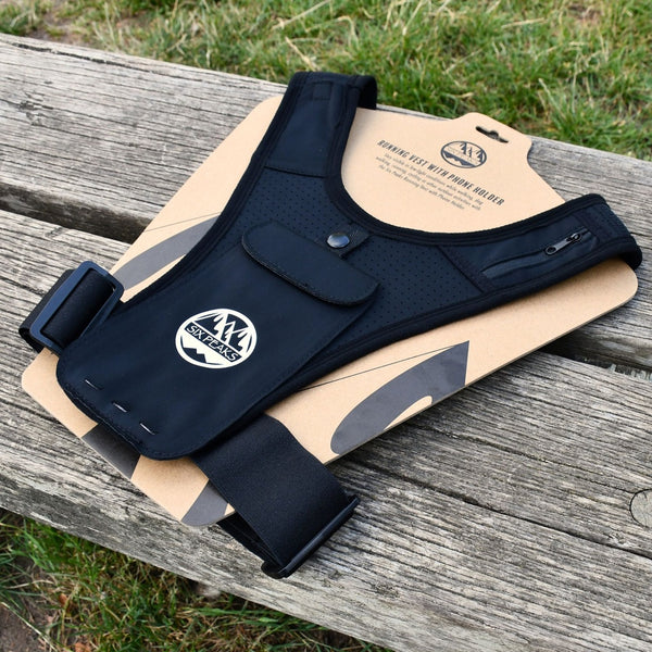 Six Peaks Running Vest with Phone Holder displayed on a cardboard packaging, resting on a wooden bench.