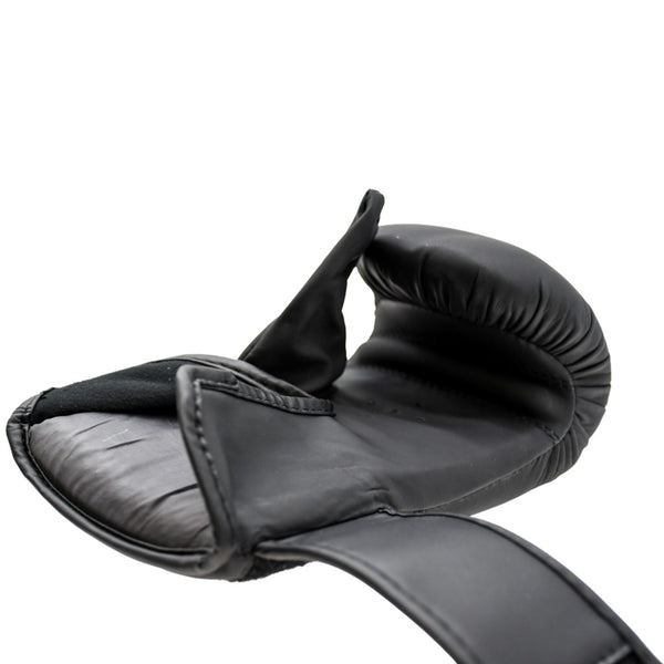 Close-up side view of a black Urban Fight punch bag mitt lying flat with the palm side and thumb visible, showing padding and open velcro strap, on a white background.