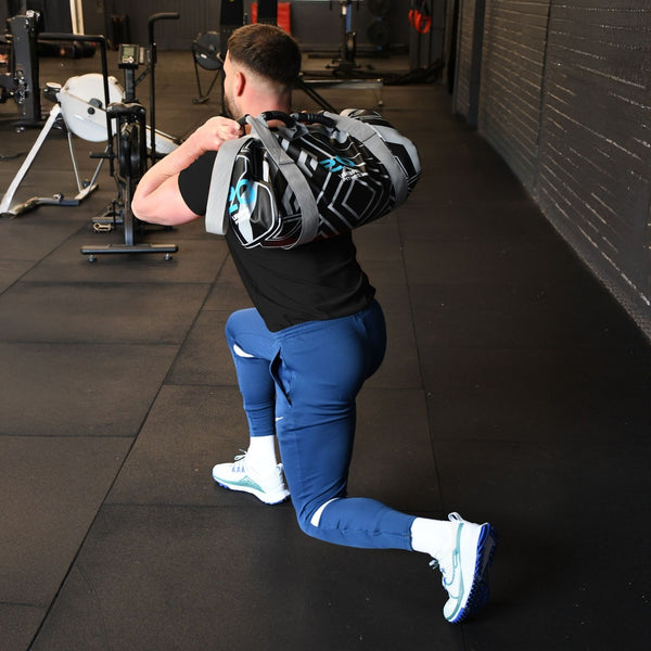 Person performing a lunge with an Urban Fitness Power Bag 20kg on their shoulders, set against a gym background