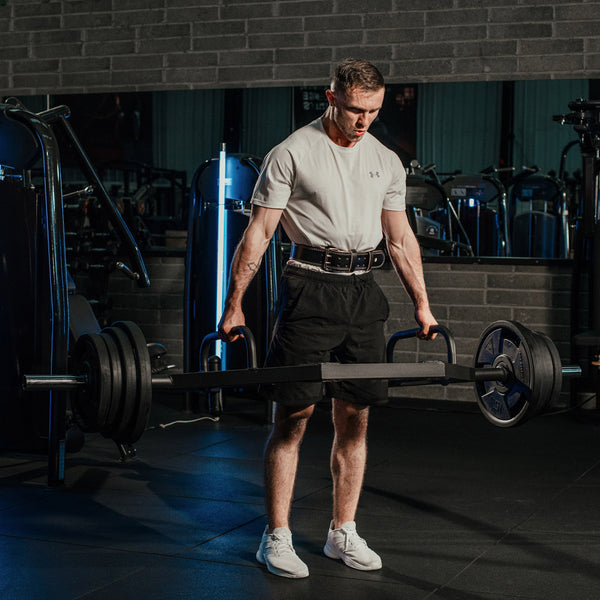 A Guy wearing the Hit Fitness Leather Weightlifting Belt while holding a Hexbar