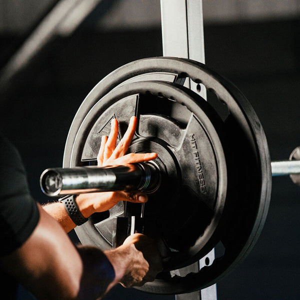 Hit Fitness Rubber Radial Olympic Weight Discs | 10kg - Man mounting Plates on a Bar